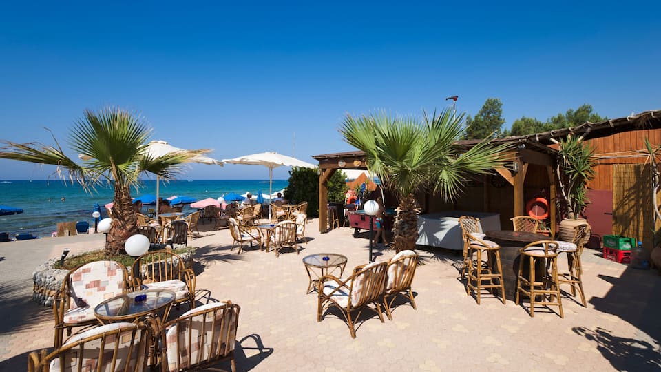 A beachside café with wicker furniture and umbrellas, overlooking the sea.