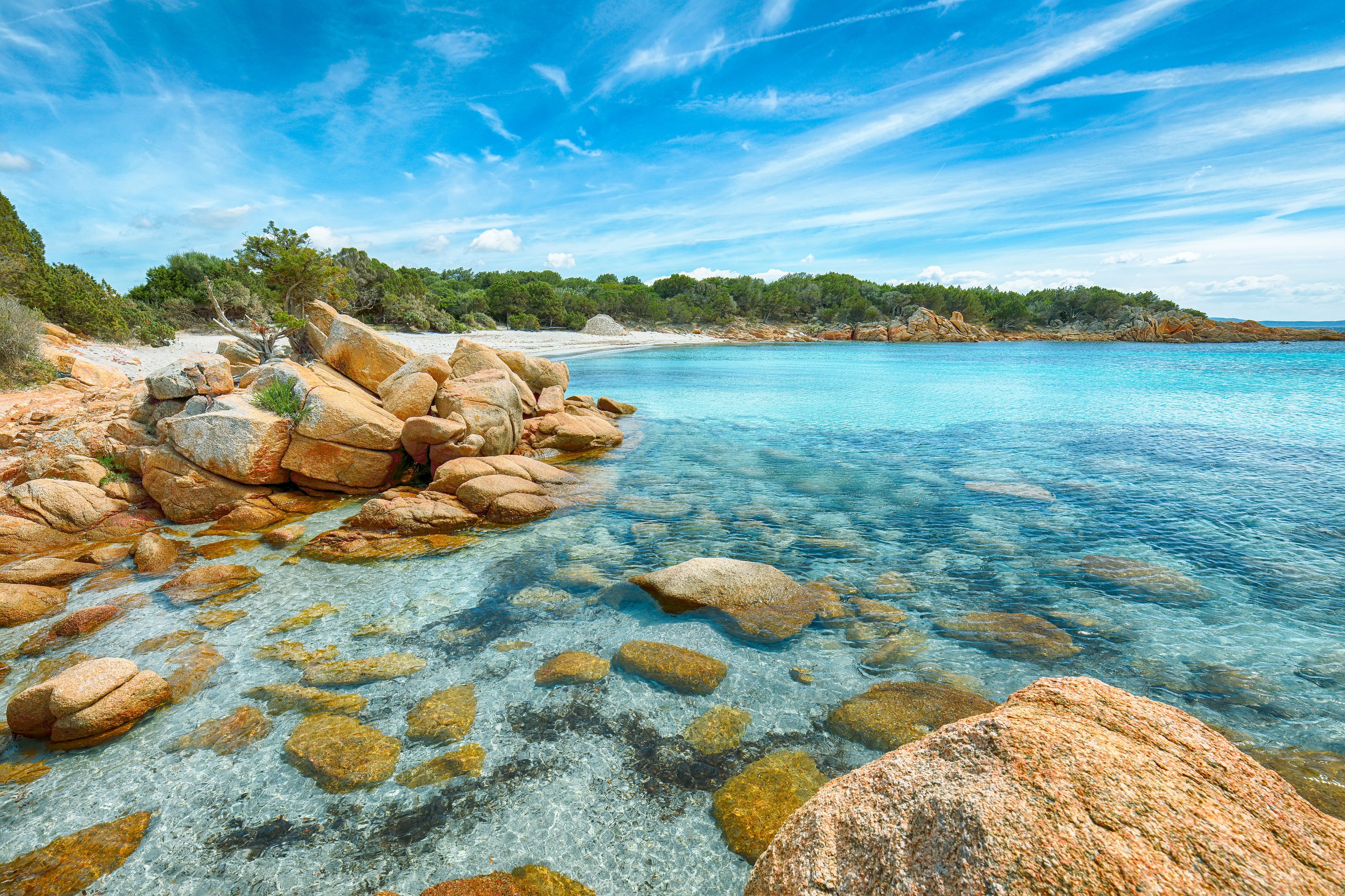 A clear coastal landscape with rocky shores and a calm sea.