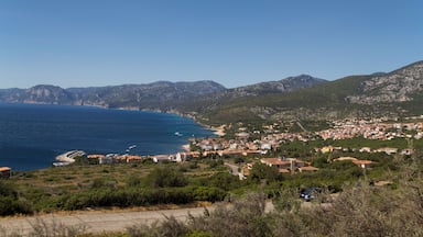Un pueblo costero con playa, montañas y un cielo azul despejado.