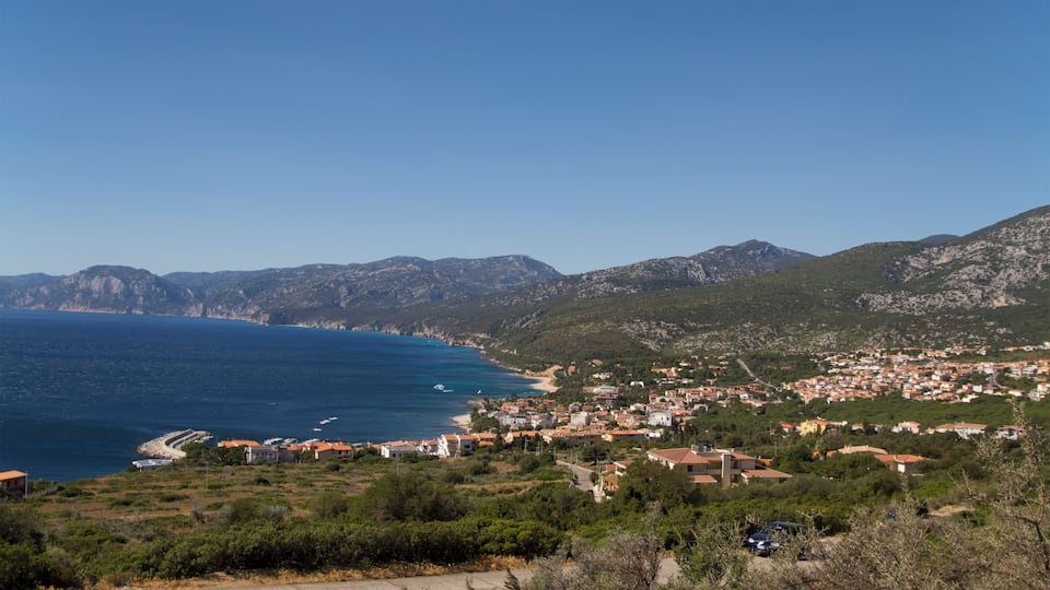 A coastal town with a beach, mountains, and a clear blue sky.