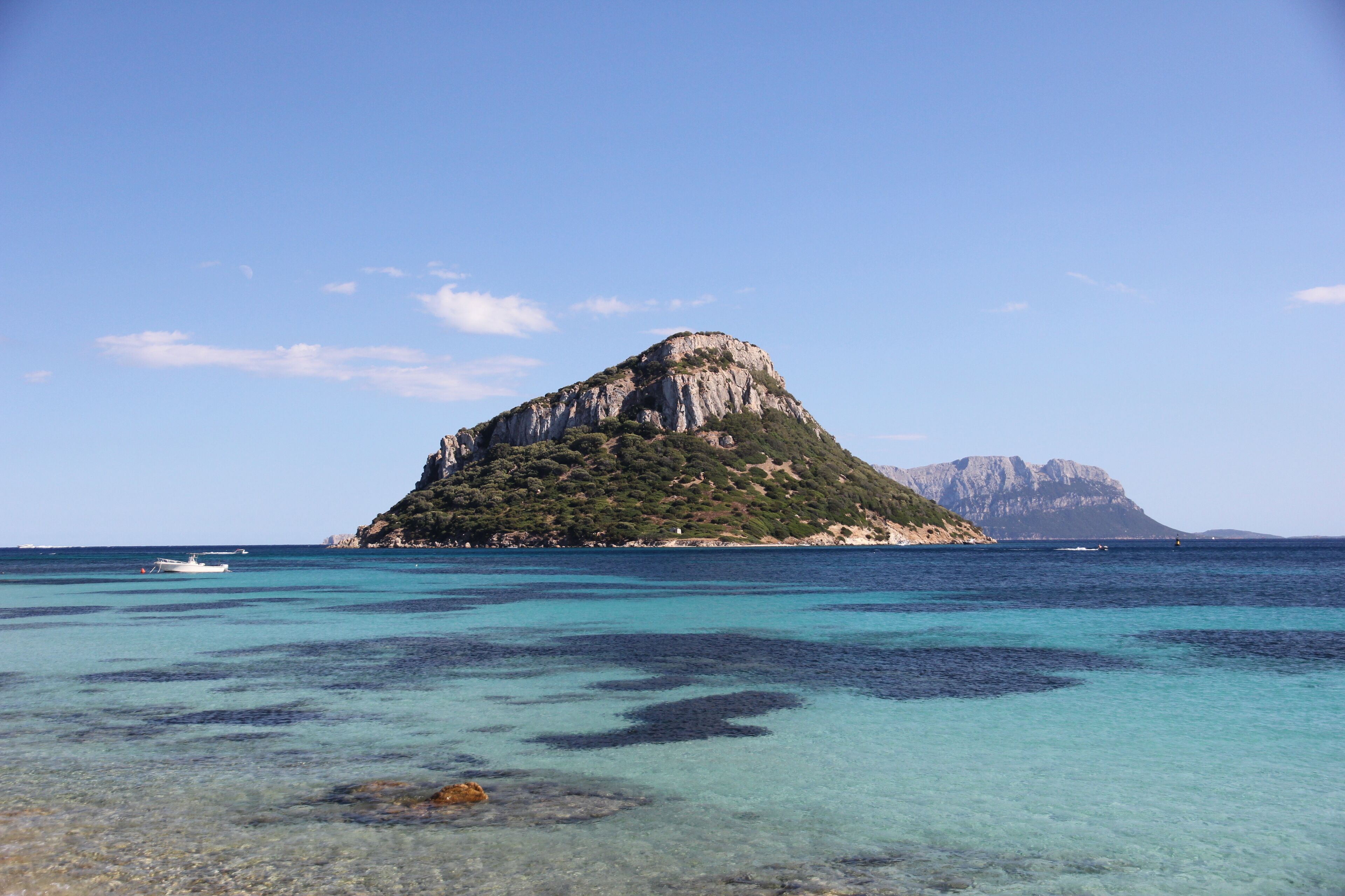 A clear turquoise sea with a small island featuring rocky cliffs and sparse vegetation.