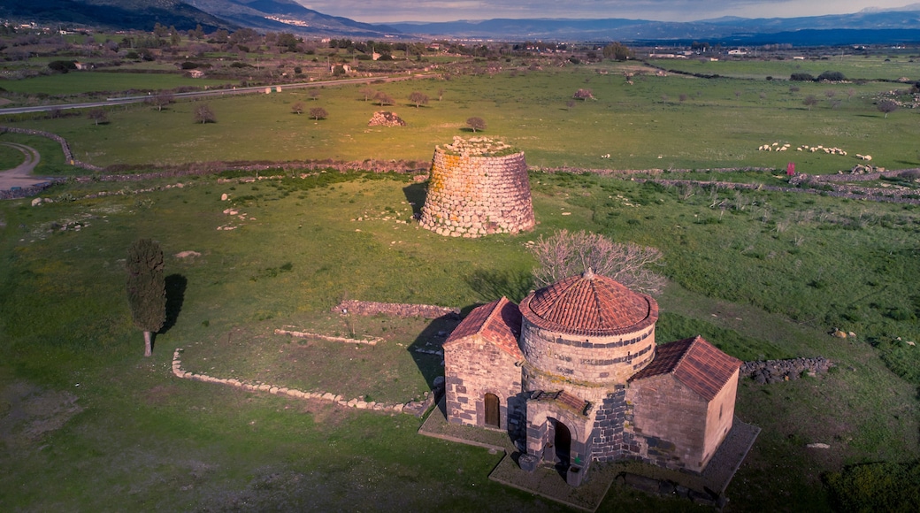 Vue aérienne d’un paysage rural avec une tour en pierre et une église dont le toit est recouvert de tuiles.