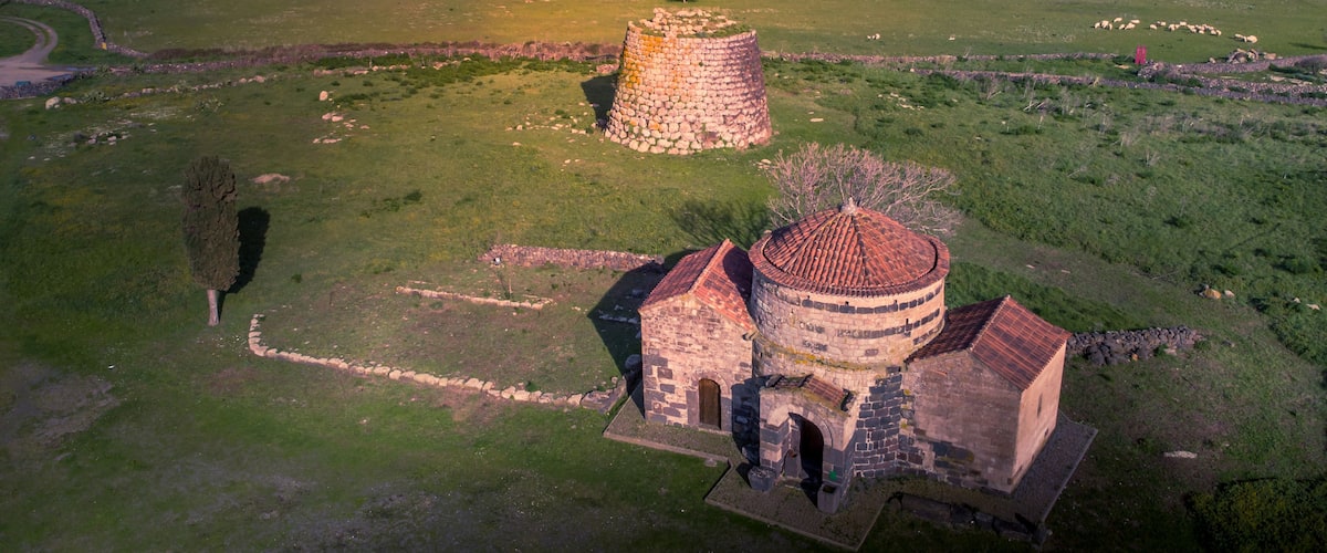 Vista aérea de uma paisagem rural com uma torre de pedra e uma igreja com telhado de telhas.