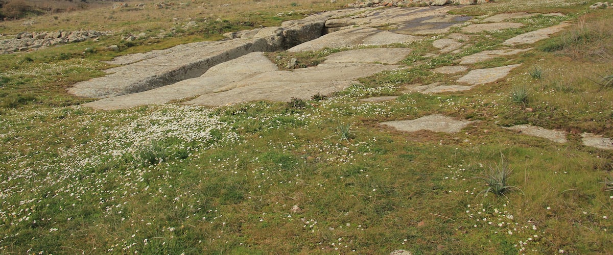 A rocky hillside with a small rock formation and a stone pathway.