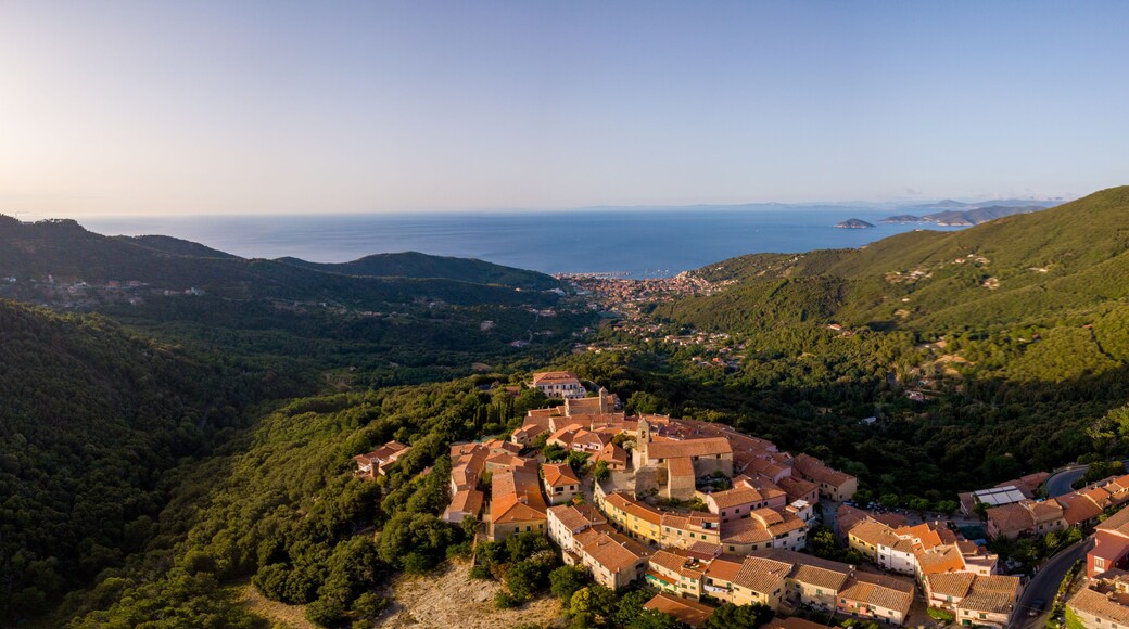 Aerial Drone Panorama of mountain old town Marciana on the islands of Elba Italy with green trees and the mediterranean sea ocean in the background