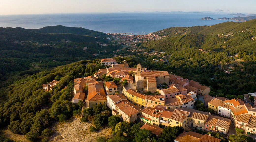 Aerial Drone Panorama of mountain old town Marciana on the islands of Elba Italy with green trees and the mediterranean sea ocean in the background