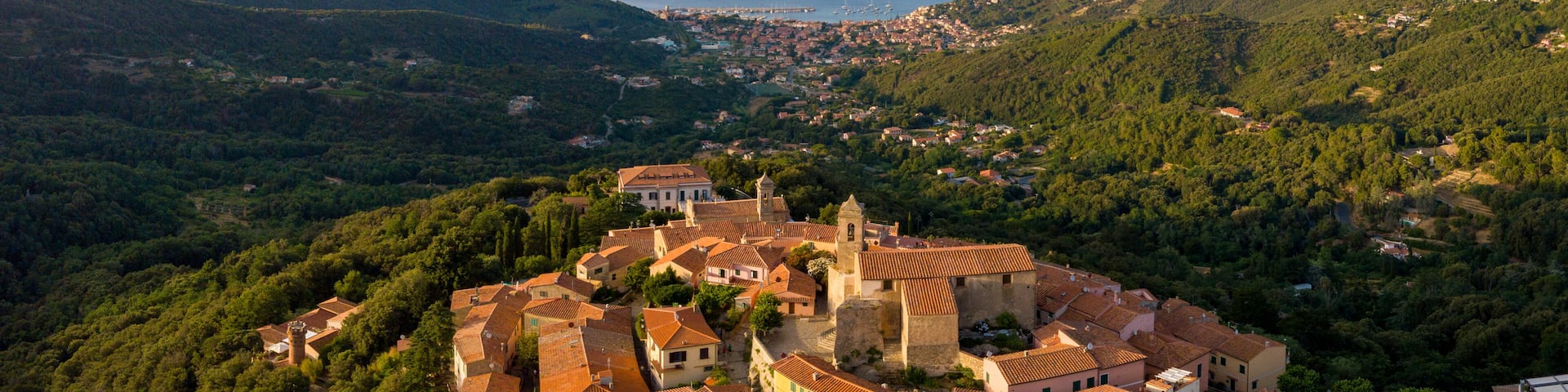 Aerial Drone Panorama of mountain old town Marciana on the islands of Elba Italy with green trees and the mediterranean sea ocean in the background