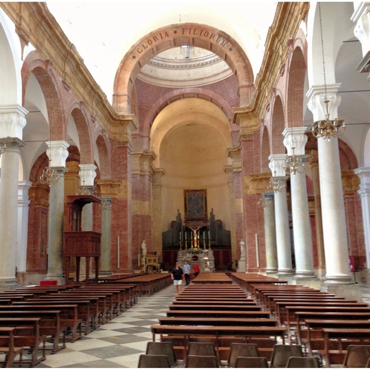 A church interior with arched ceilings, wooden pews, and a central altar.