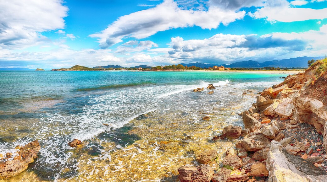 The Nora bay and beach, the medieval Sant'Efisio church near the shore and mountains in the background
