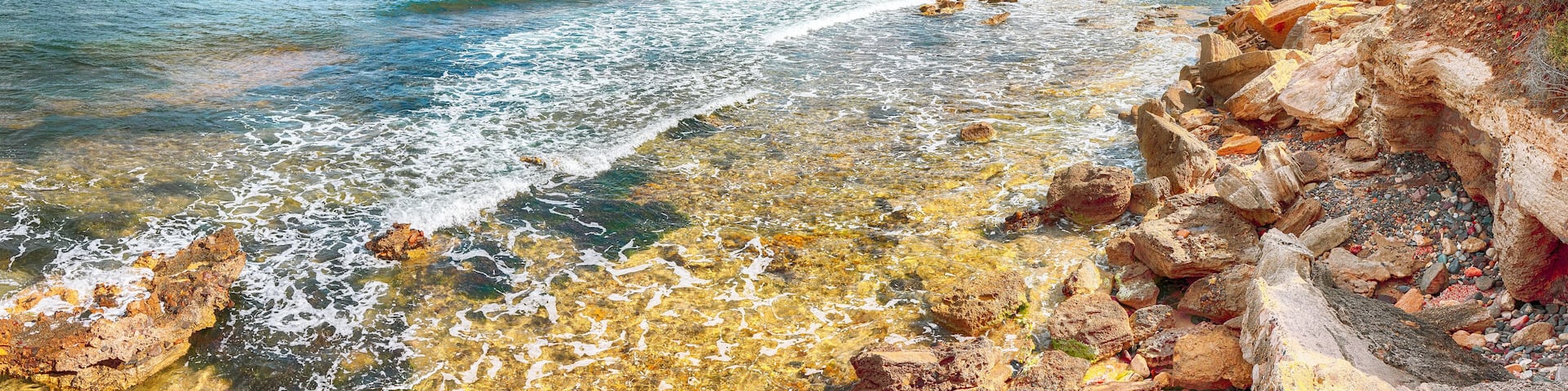 The Nora bay and beach, the medieval Sant'Efisio church near the shore and mountains in the background