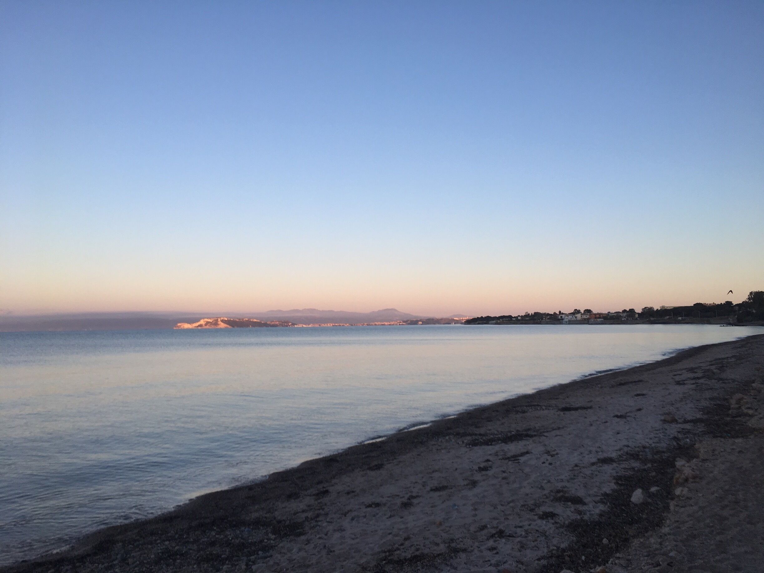 A beach with calm water and a clear sky.