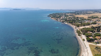 Un pueblo costero con aguas azules cristalinas, una playa de arena y edificios residenciales a lo largo de la costa.