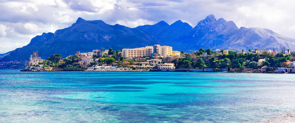 A coastal town with buildings and mountains in the background.