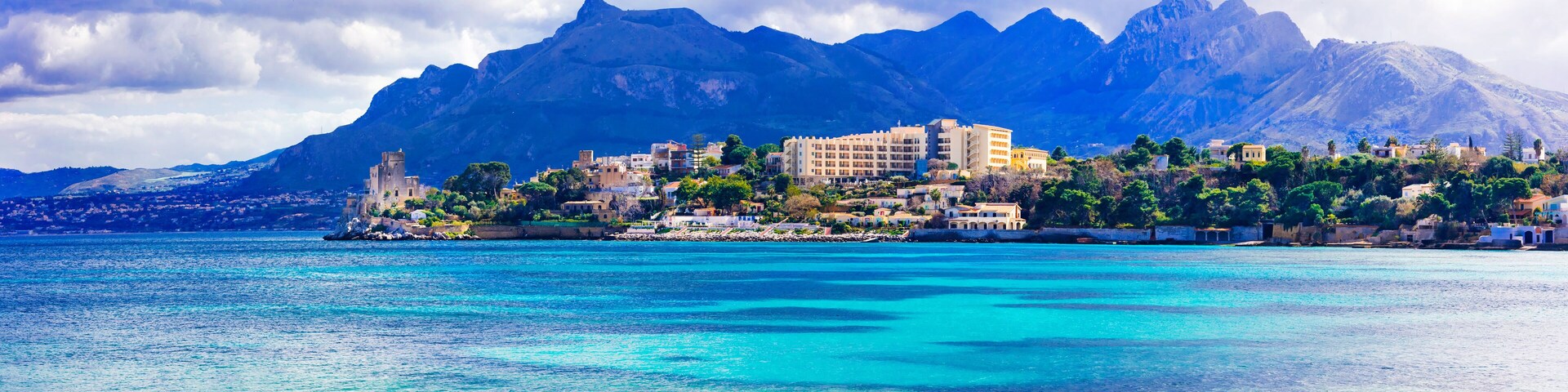 A coastal town with buildings and mountains in the background.