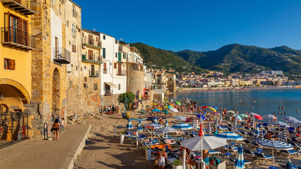 A coastal town with historic buildings, a sandy beach, and a clear blue sea.