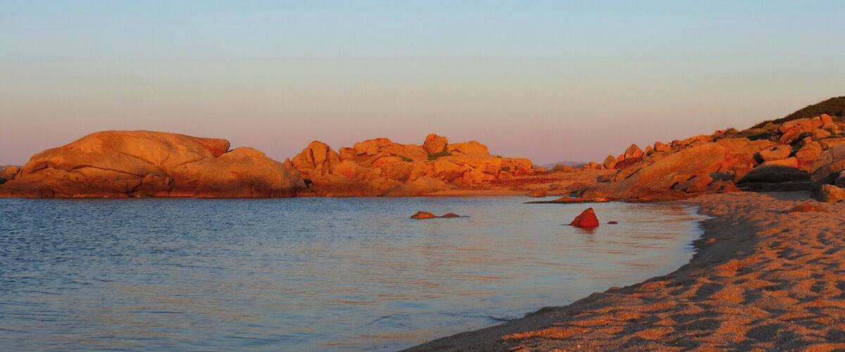 A coastal landscape with large rock formations and calm waters.