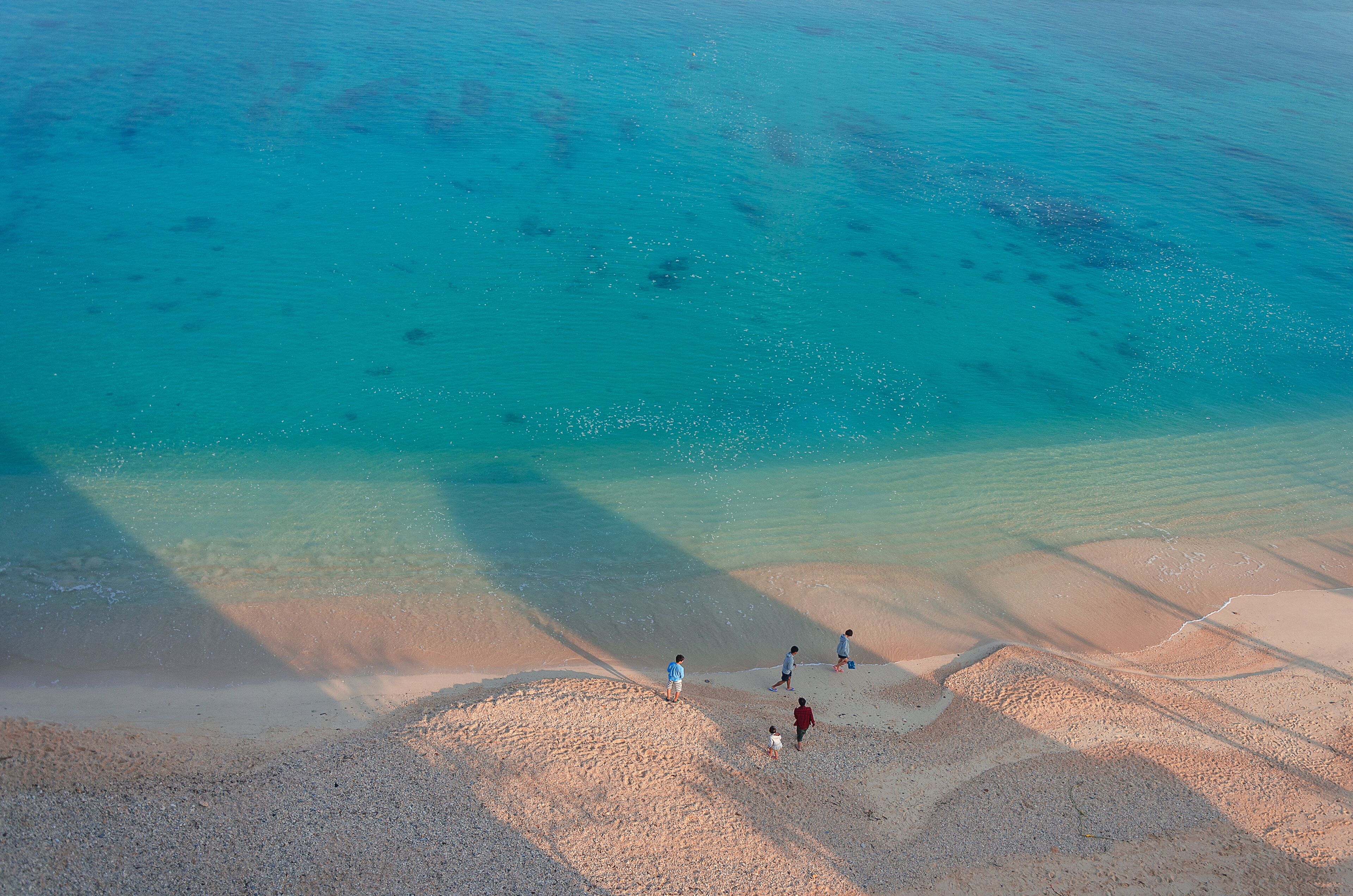 Several people on the beach of Kouki in Nago on Okinawa island in Japan. Beautiful turquoise water color of the South China sea.