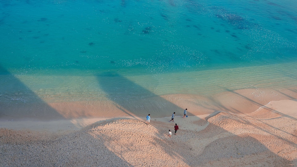 Several people on the beach of Kouki in Nago on Okinawa island in Japan. Beautiful turquoise water color of the South China sea.