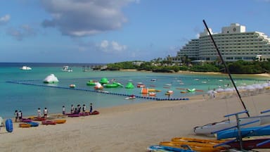 A beach with colorful kayaks and canoes, a large hotel, and a calm sea.