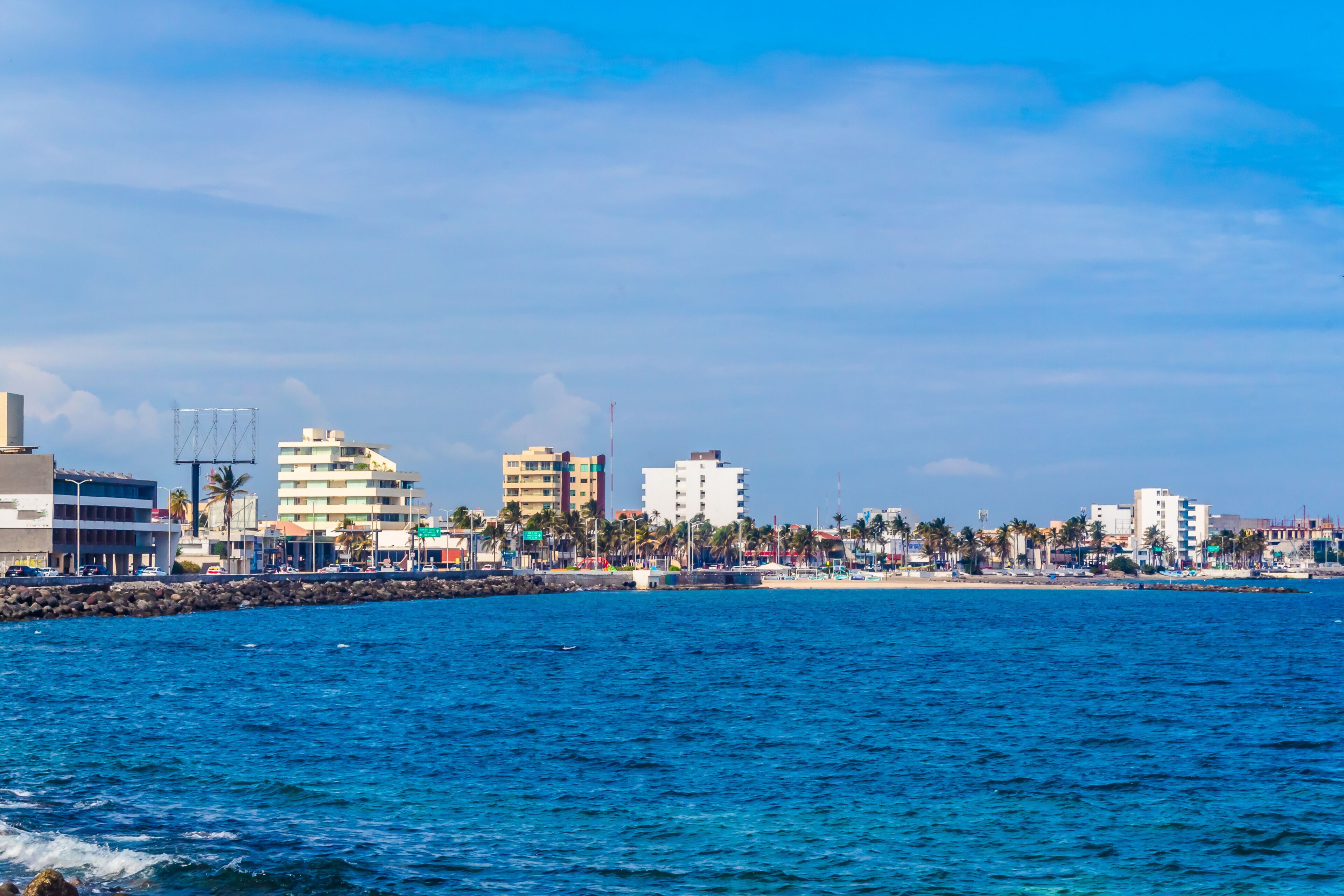 Un paisaje urbano costero con edificios, una playa y palmeras.