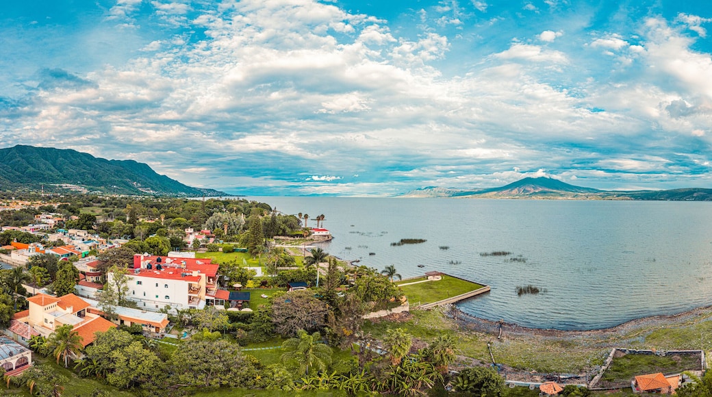 A panorama of mountains and lake with the sunset as background. Clouds and blue sky with trees and colors
