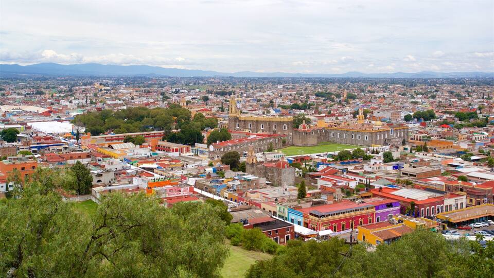 A panoramic view of a city with a prominent historical building and a mountainous backdrop.