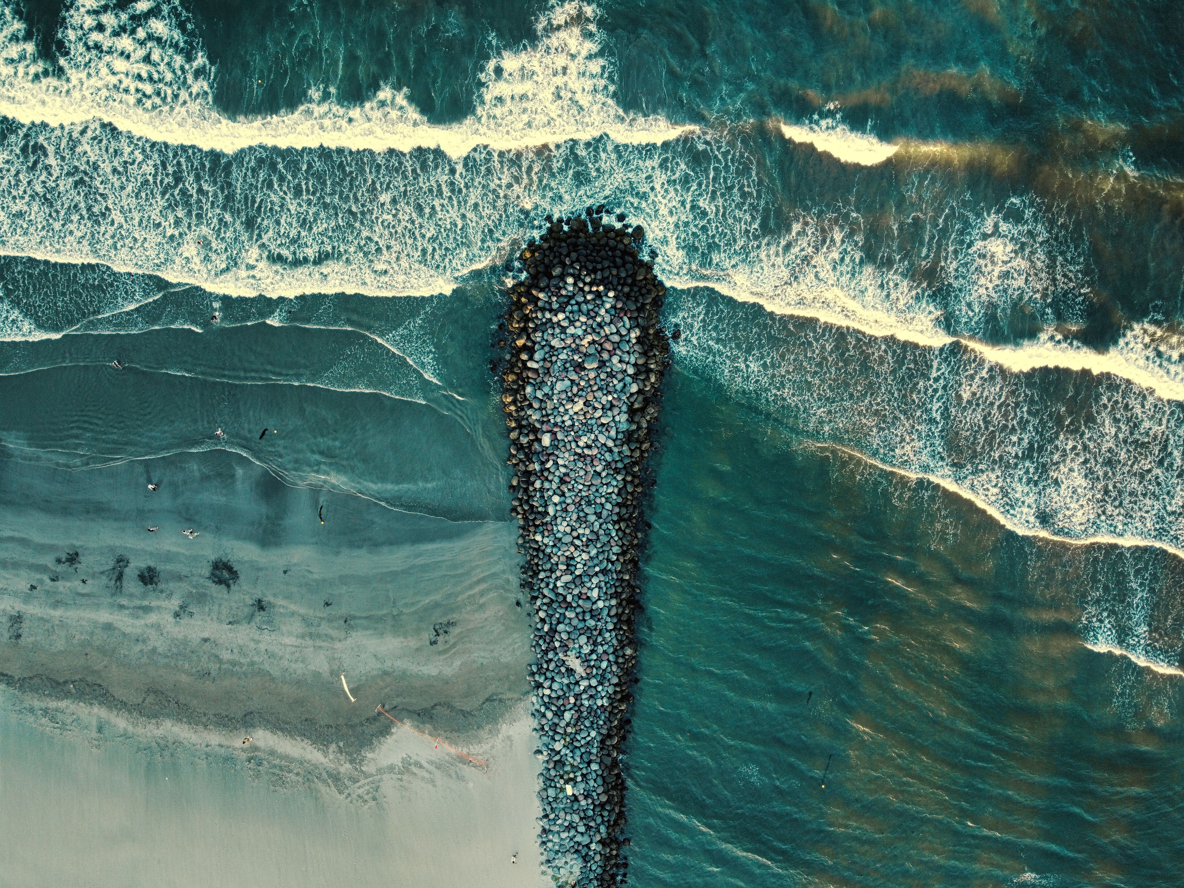 A coastal landscape with a rocky shoreline and waves crashing onto the beach.