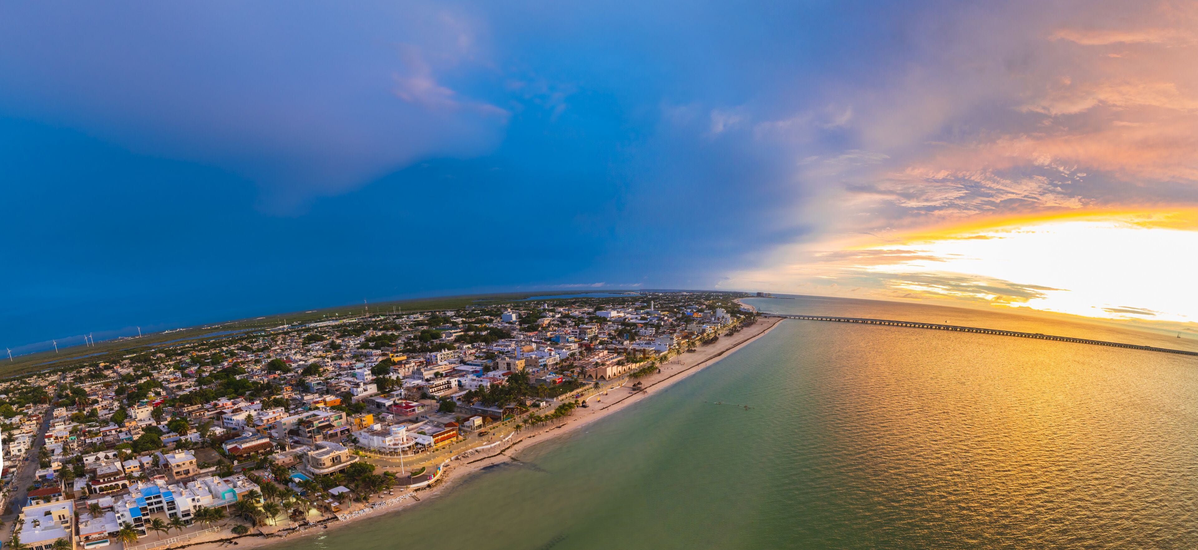 Aerial view of the vivid contrast between the dark blue sky and the warm sunset over the ocean and the cityscape, Progreso, Yucatan, Mexico.