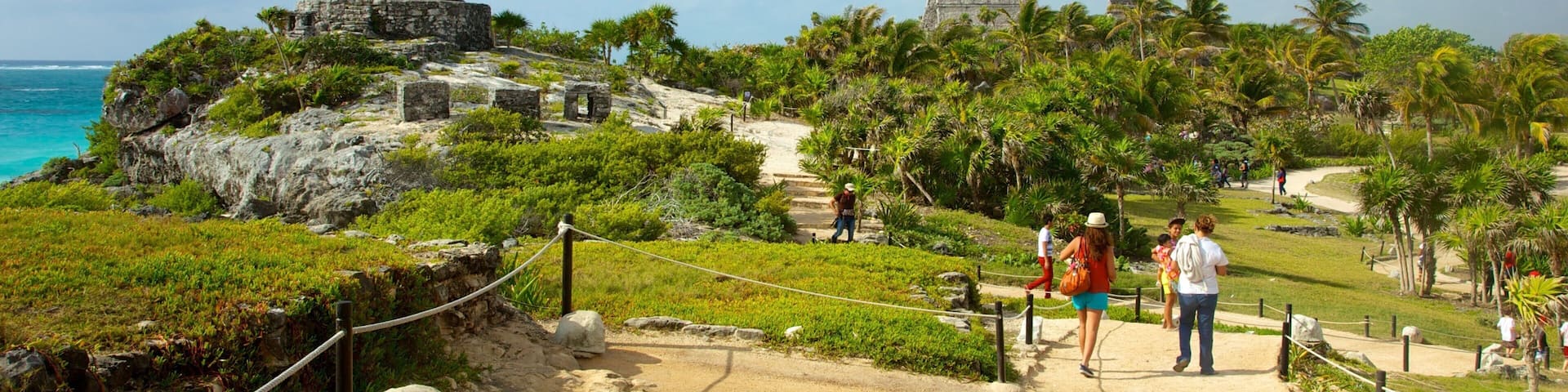 A coastal archaeological site with ruins and a pathway leading to them.