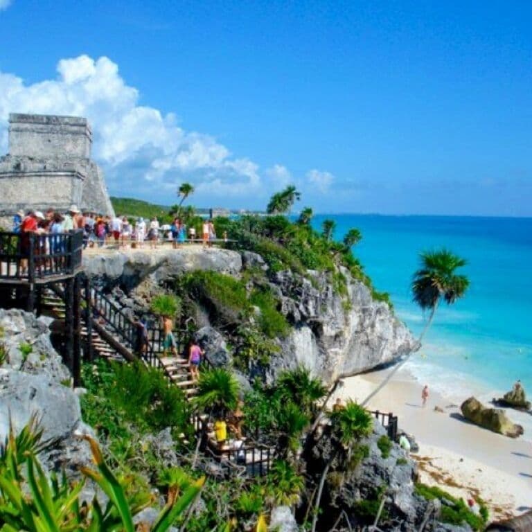 A coastal scene with a stone structure, a beach, and palm trees.