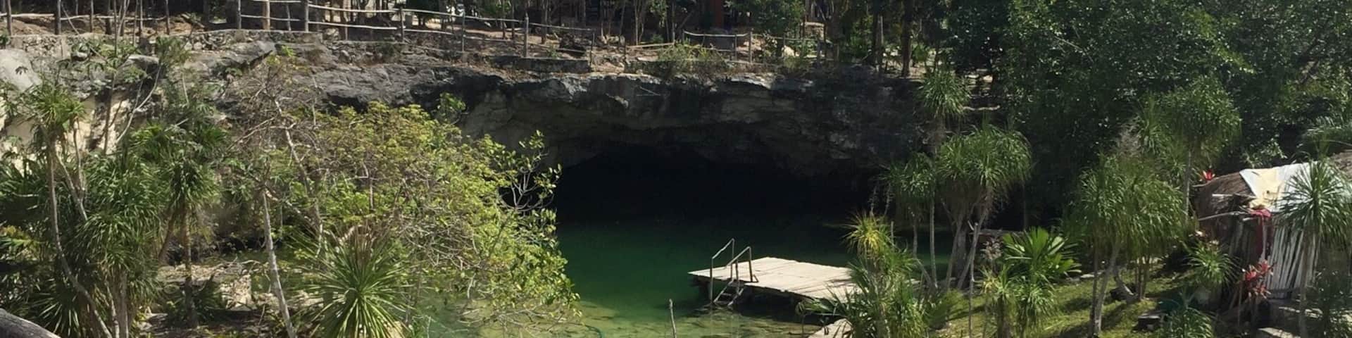 A rocky terrain with a small water body, wooden structures, and dense greenery.