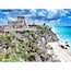 A coastal area with a historical stone structure, a beach, and clear blue waters.