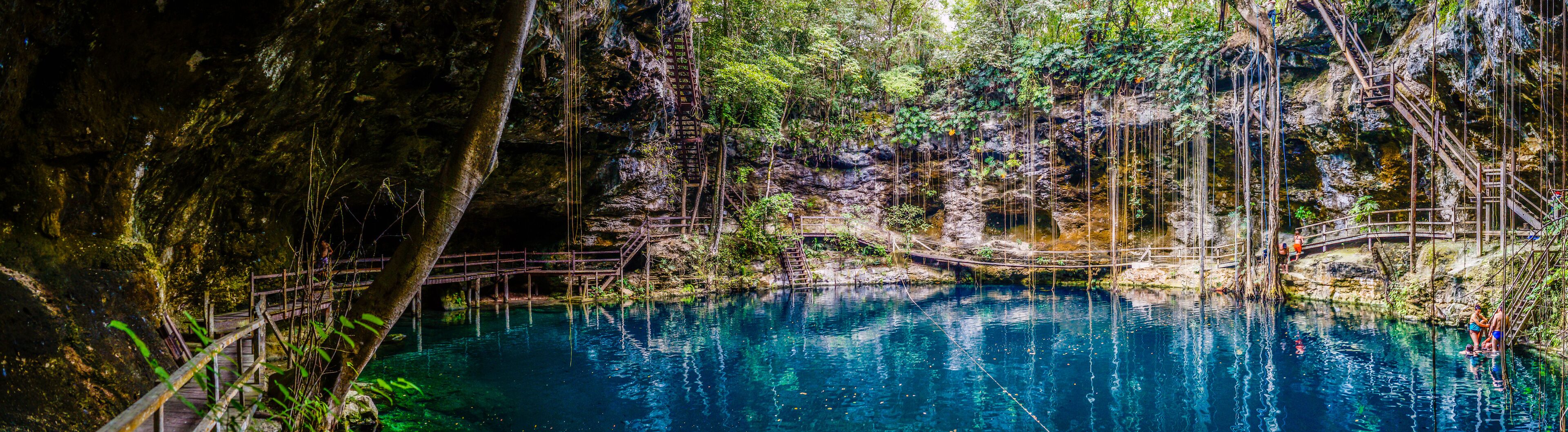 A clear blue pool surrounded by rocky cliffs and wooden walkways.