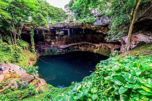 Une piscine naturelle entourée d’une végétation luxuriante et de falaises rocheuses.