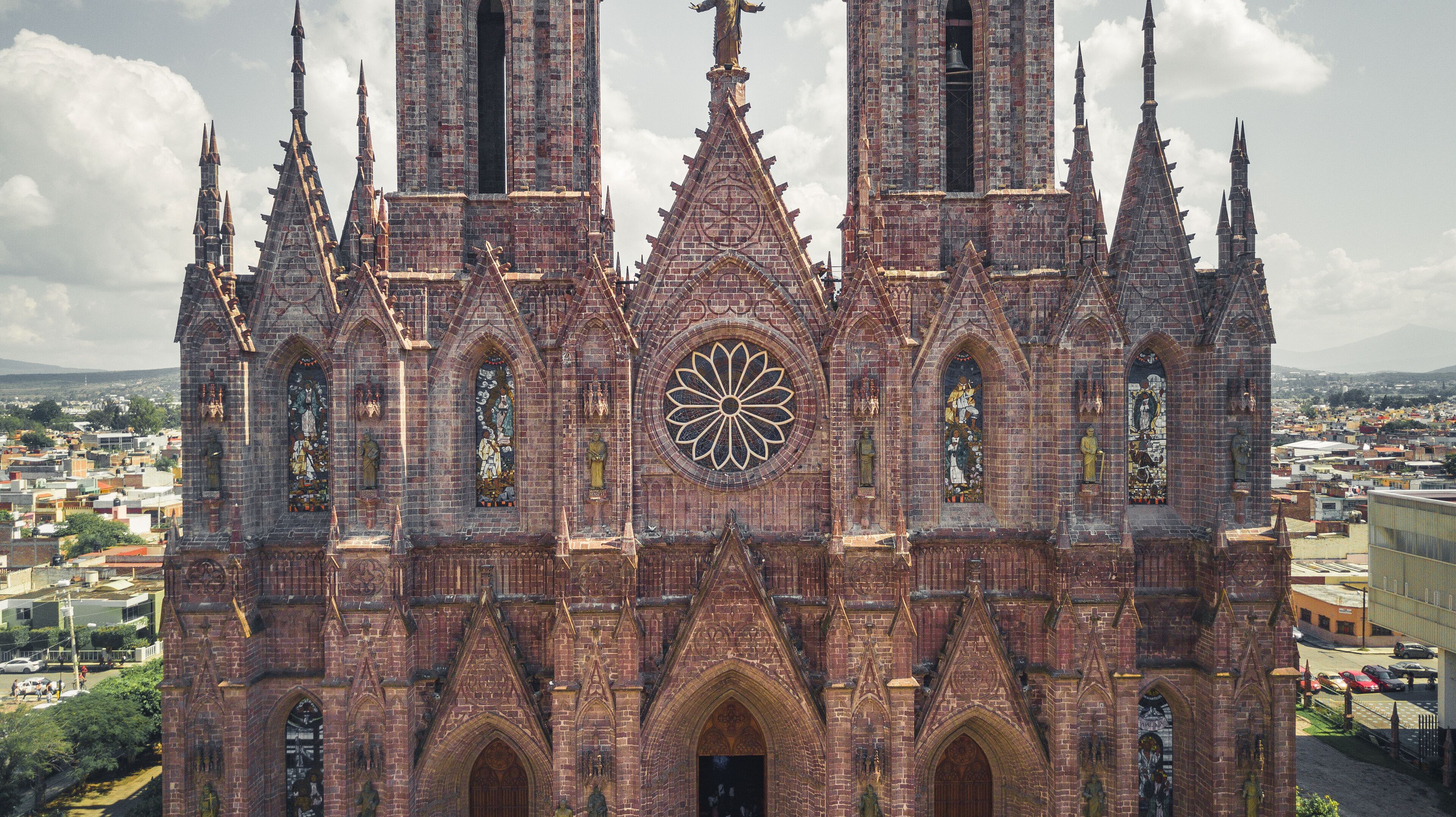 A Gothic cathedral with intricate brickwork, pointed arches, and a large rose window.