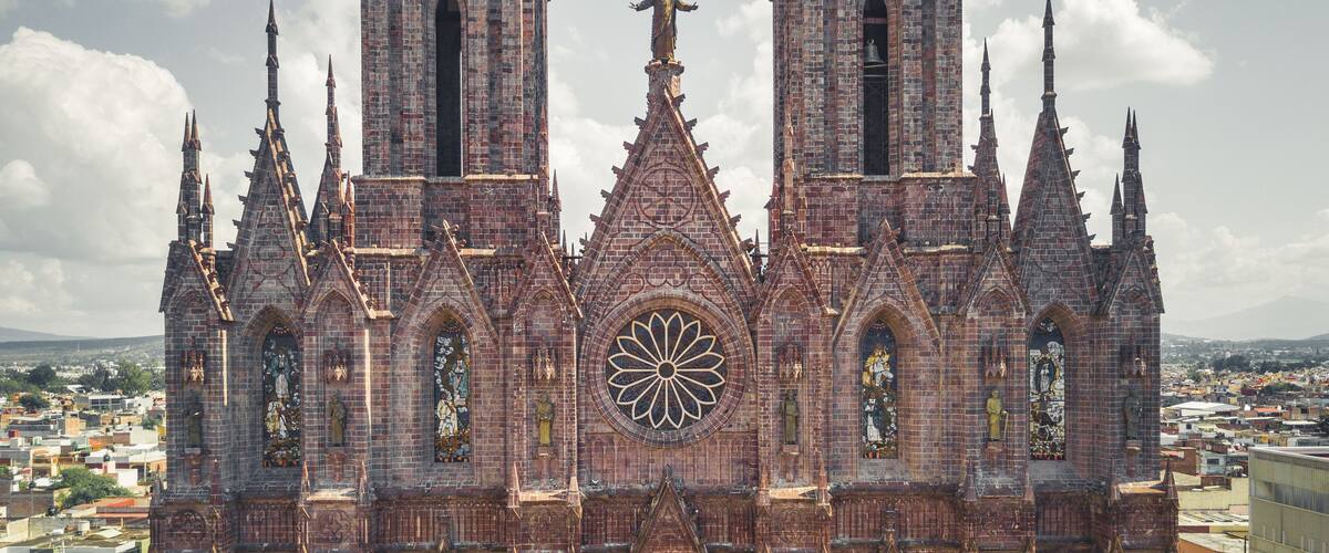 A Gothic cathedral with intricate brickwork, pointed arches, and a large rose window.