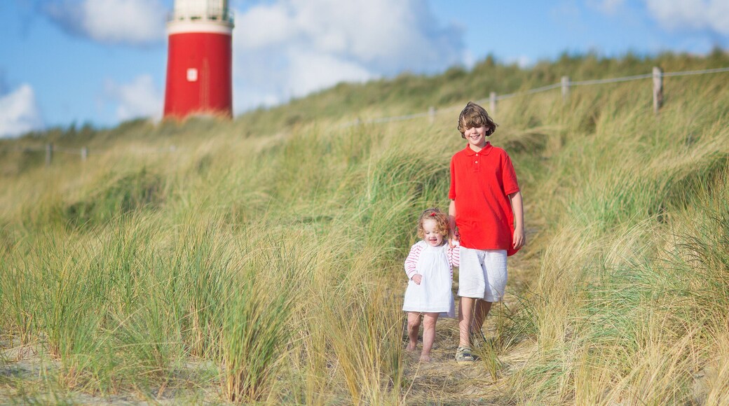 Brother and sister walking on the beach next to lighthouse