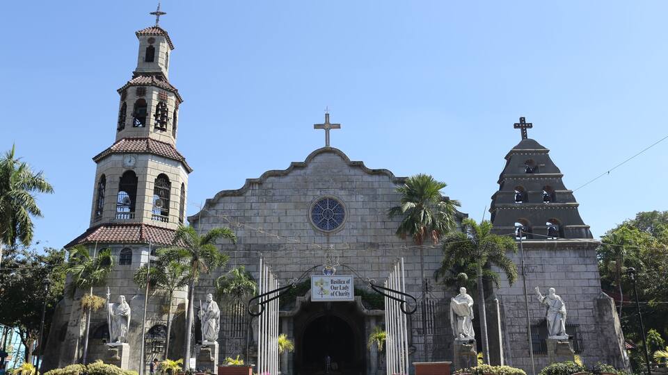 A historic church with a bell tower, a central dome, and statues of saints.