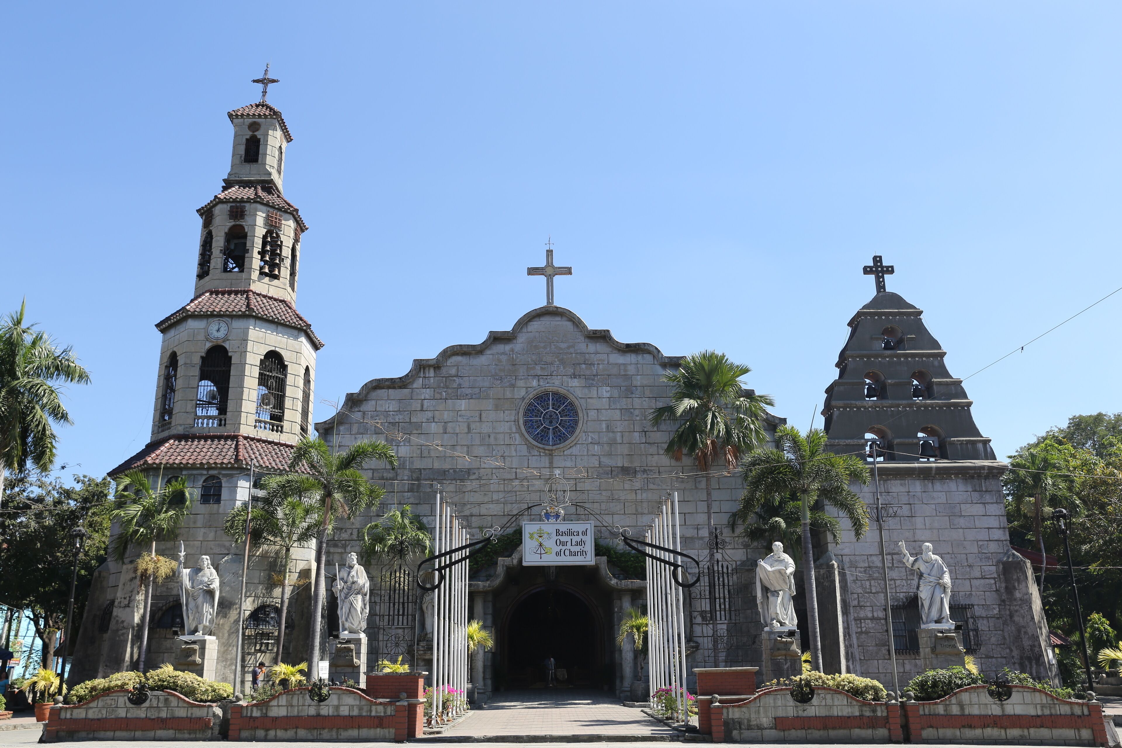 A historic church with a bell tower, a central dome, and statues of saints.