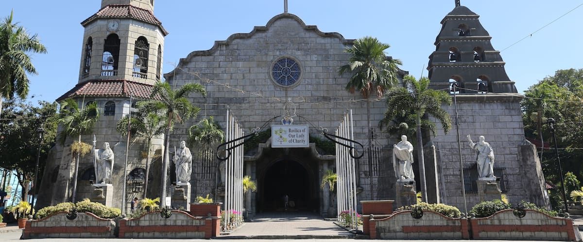 A historic church with a bell tower, a central dome, and statues of saints.