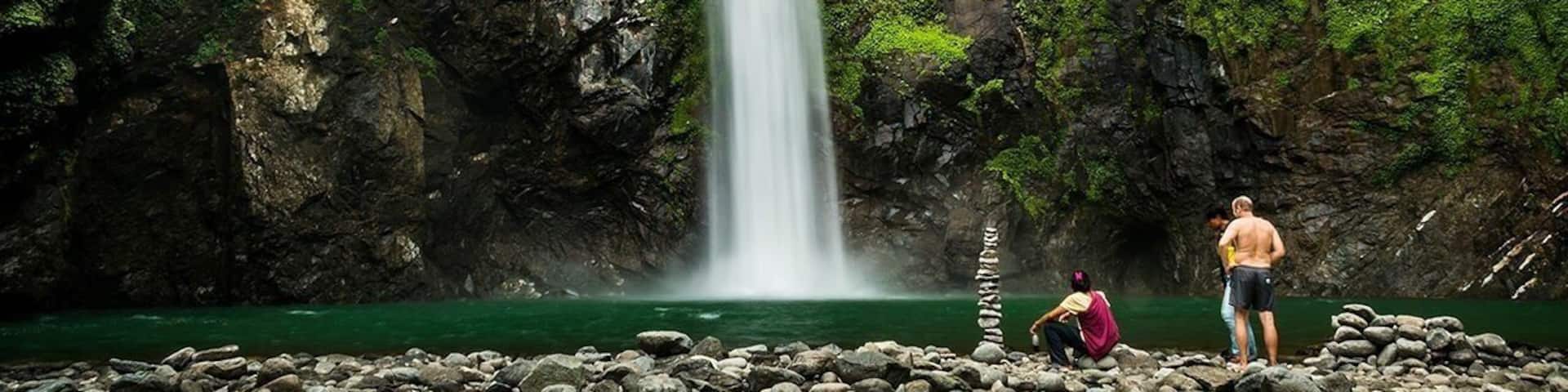 A waterfall cascading down a rocky cliff surrounded by lush greenery.