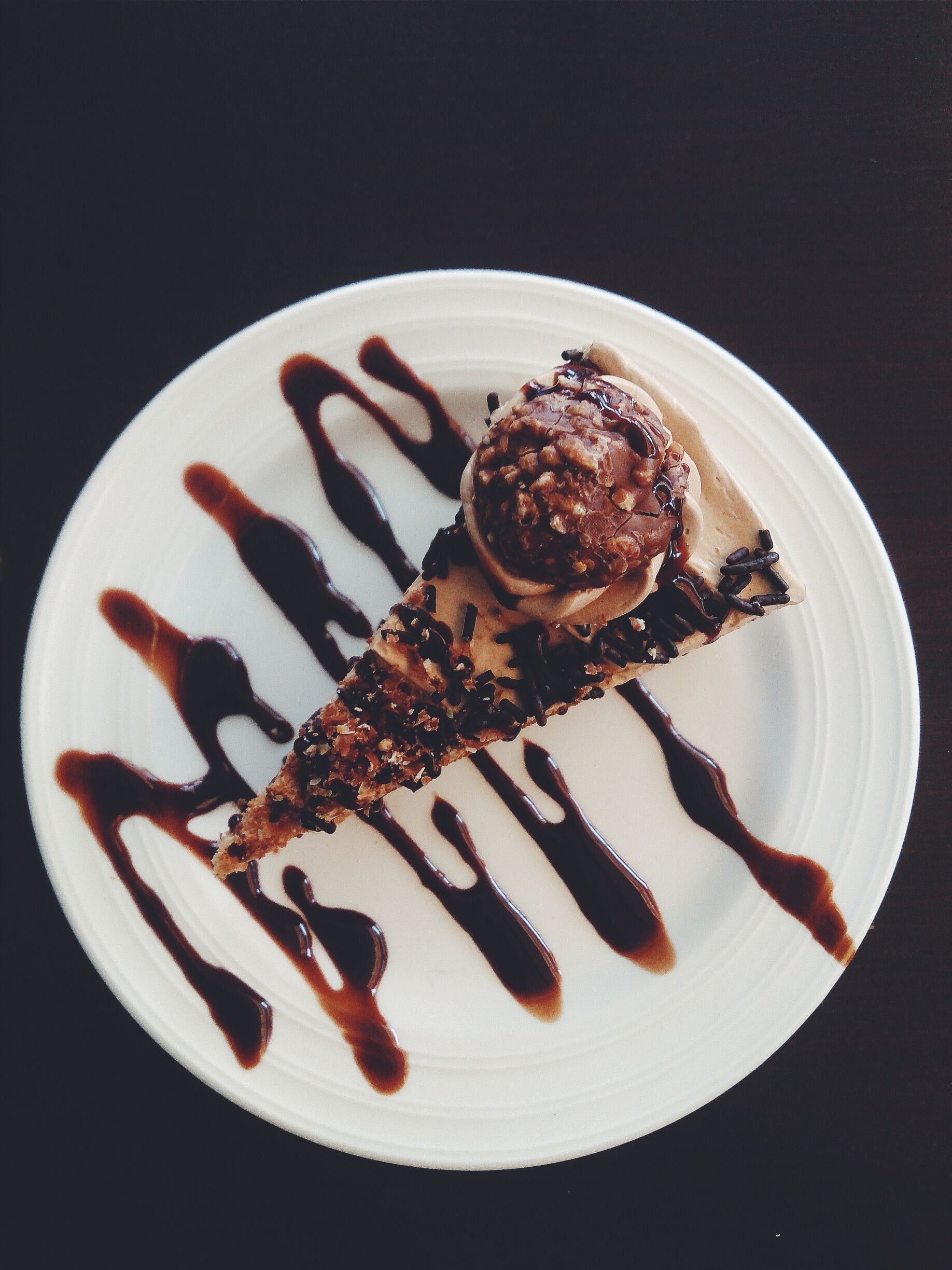 A dessert on a white plate with chocolate sauce.