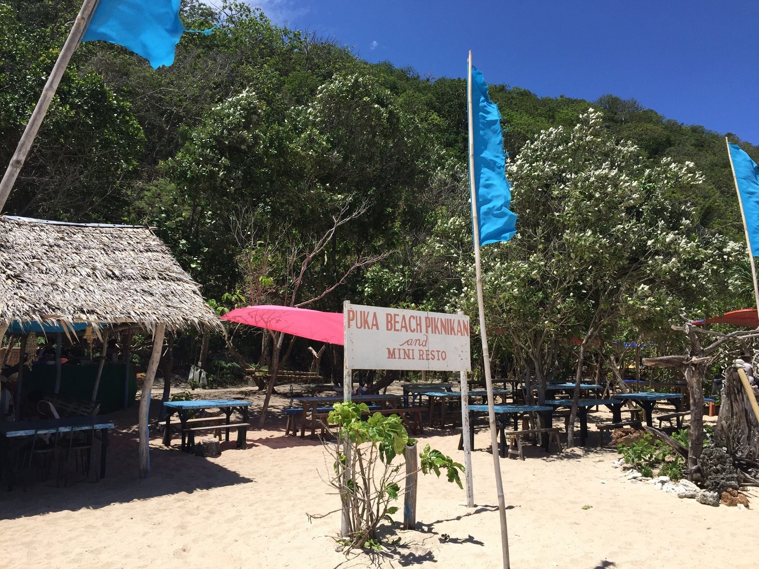 A beach with a sign reading "PUKA BEACH PIKNIKAN and mini resto".