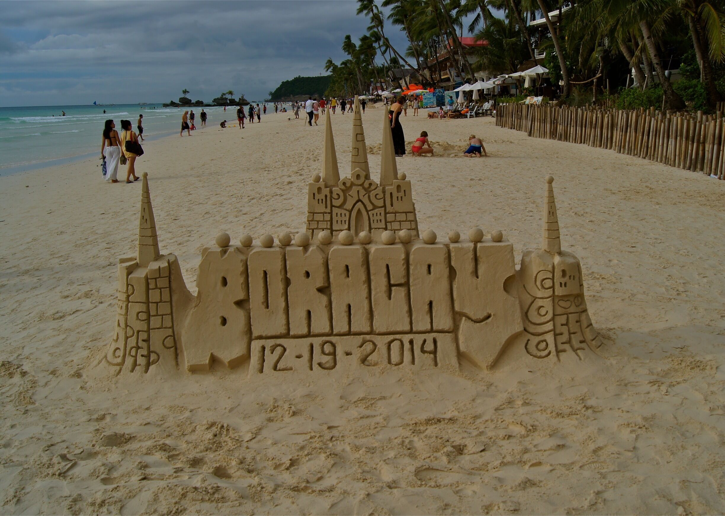A sandcastle with the word "Boracay" and the date "12-19-2014" on a beach.