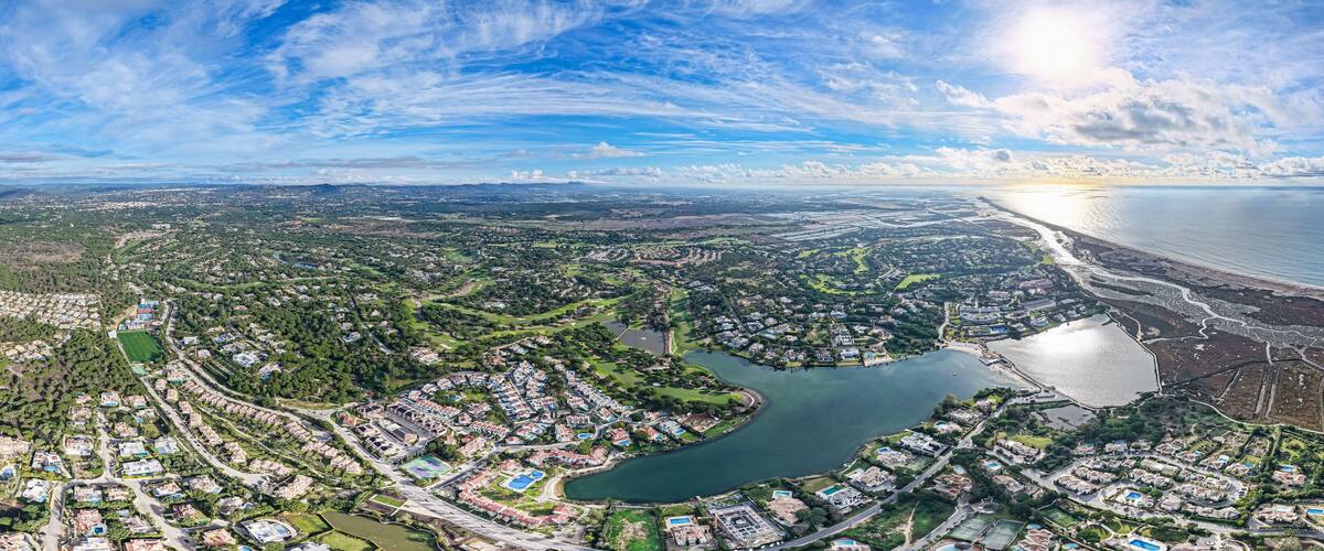 An aerial view of a coastal city with a river, residential areas, and a beach.
