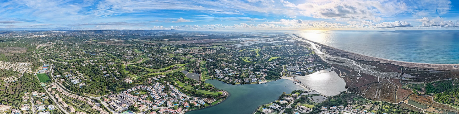 An aerial view of a coastal city with a river, residential areas, and a beach.