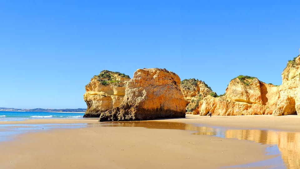 A beach with large rock formations and calm waters.