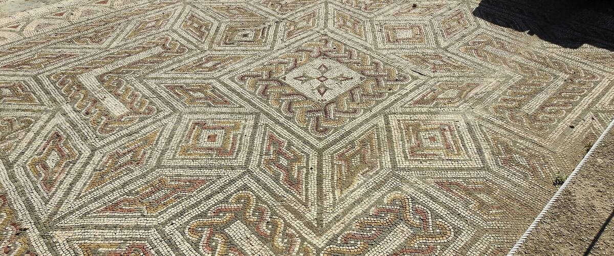 A detailed mosaic floor with geometric patterns and a central diamond shape.