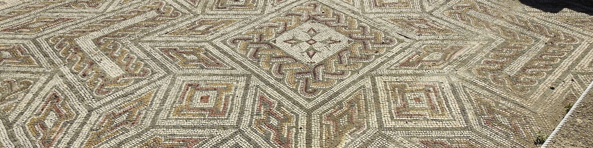 A detailed mosaic floor with geometric patterns and a central diamond shape.