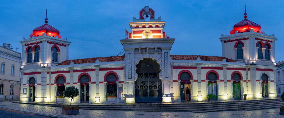 A historic building with two red domes, a central clock tower, and a large arched entrance.